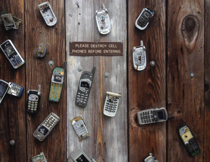 Old cellphones spread out on a wooden table.